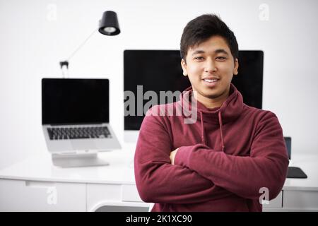 Having a good workstation will aid him in his studies. A smiling young student with his desk behind him. Stock Photo