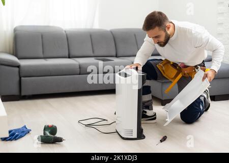young man changing - fixing a dirty air purifier HEPA filter after using for a long time. A repairman replacing and installing the air purifier filter Stock Photo