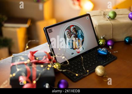 Big family singing christmas song at tablet camera during online video call. Smiling parents and children. Joyful family congratulating relatives with Stock Photo