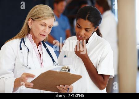 Your patient is recovering well. two doctors discussing a patients diagnosis. Stock Photo