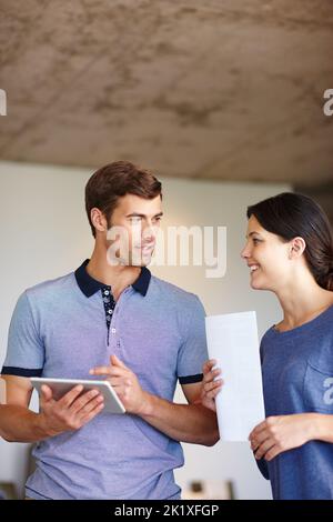 The technological team. a man using a digital tablet while his wife stands by with a document. Stock Photo