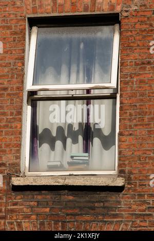 A partially opened window at a red brick property. Stock Photo