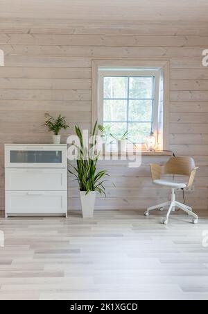 Stylish Scandinavian living room or bedroom with designer furniture, plants, dresser and chair. Wooden light finishing of walls and floor. Stock Photo