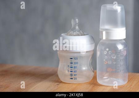 Nursing bottles for newborn baby on wooden table. Preparing milk for baby feeding. Empty space for text. Stock Photo
