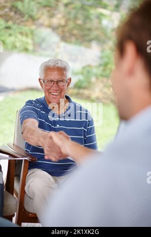 Pleased with good advice. Over-the-shoulder shot of two men shaking hands. Stock Photo