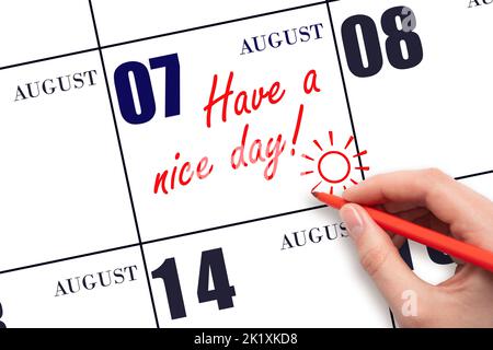 7th day of August. The hand writing the text Have a nice day and drawing the sun on the calendar date August 7. Save the date. Summer month, day of th Stock Photo