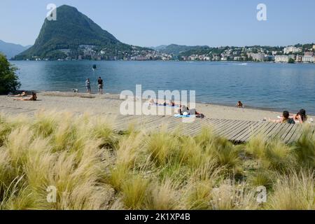Lugano, Switzerland - 19June 2022: people sunbathing on the beach at Lugano on Switzerland Stock Photo