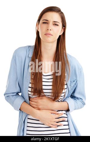 These cramps are unbearable. Studio shot of an attractive young woman suffering from abdominal pain against a white background. Stock Photo