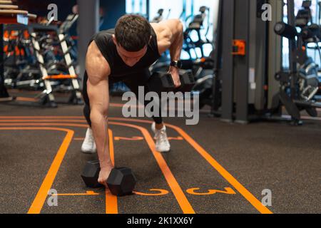 Athletic man doing dumbbell plank row in fitness gym. Fitness gym training. Fitness strength workout Stock Photo
