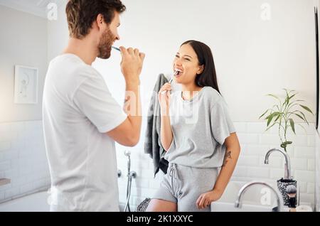 Love, morning and couple in bathroom brushing teeth together doing daily routine, happy and smile. Man and woman with good dental health, mouth care Stock Photo