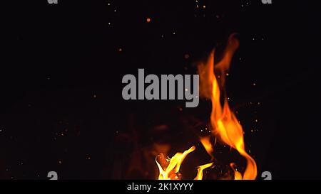 Fire flames and a lot of bright sparks are flying from the fire at black background Stock Photo