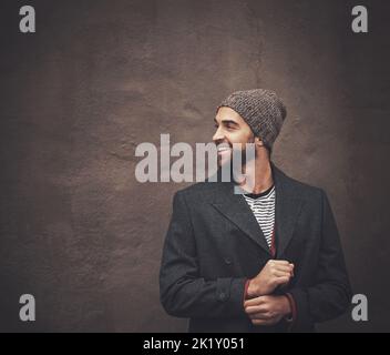 Winter style. a fashionable young man standing against a dark wall. Stock Photo