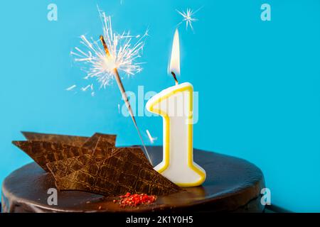 Number 1 birthday candle burning and sparkler with sparks fly on cake. The first birthday of anniversary celebration concept. Lot of copy space. Stock Photo