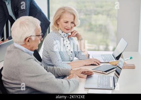 A senior woman and senior man learn and discuss the use of technology in the retraining course in the classroom. Stock Photo