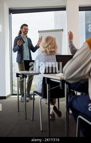 Young educator teaching a multicultural group of senior students in the classroom. Stock Photo