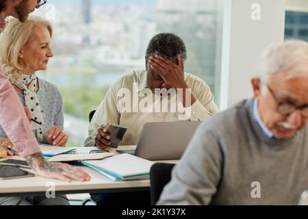 A senior african man having trouble learning the use of the internet on the course for senior people in the classroom. Stock Photo