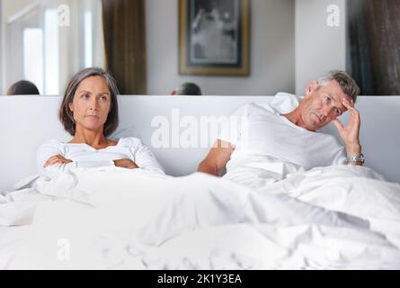 Theyre not talking to each other...a mature married couple upset with each other in the bedroom. Stock Photo
