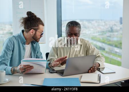 A young teacher explaining to senior student how do computer programming on a laptop. Stock Photo