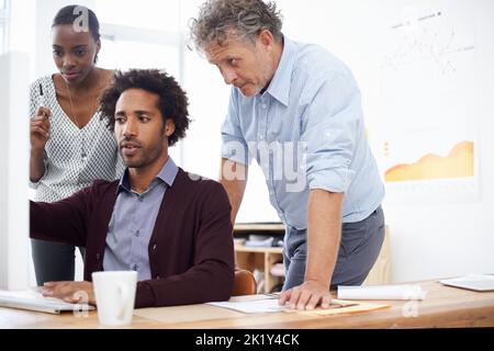 Finding solutions together. A designer showing his latest work to two of his coworkers. Stock Photo