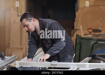 Side view portrait of young male worker using wood cutting machine in workshop Stock Photo