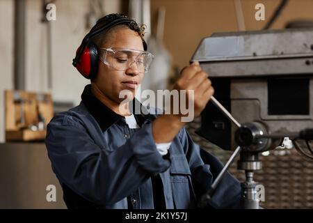 Portrait of female worker operating machine units in industrial workshop, copy space Stock Photo