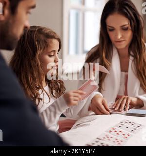 My turn. a young family playing cards together at home. Stock Photo