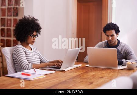 Life online. a young couple busy on their laptops at home. Stock Photo