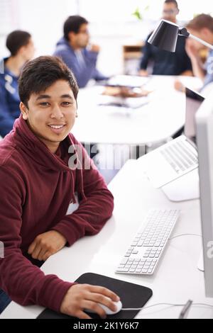 He always keeps a cool head in the face of a deadline. a young man working on his laptop in an office. Stock Photo