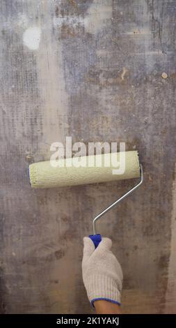 Painters hand holds paint roller, painting wall with white color. Close-Up Of Hand Painting Wall. Hand holds roller close-up. Stock Photo