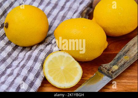 Whole and sliced Lemons on a cloth and wood background with cutting knife Stock Photo