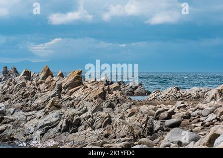 sharp jagged basalt rocks on the sea coast, Cape Stolbchaty on Kunashir ...