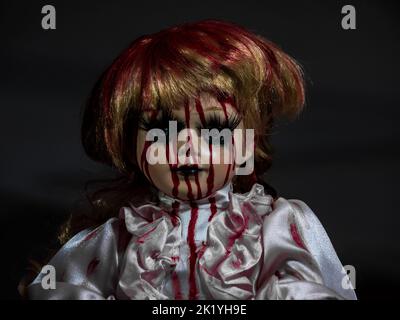 horror style porcelain blonde hair doll face in darkness covered in blood, retro doll style Stock Photo