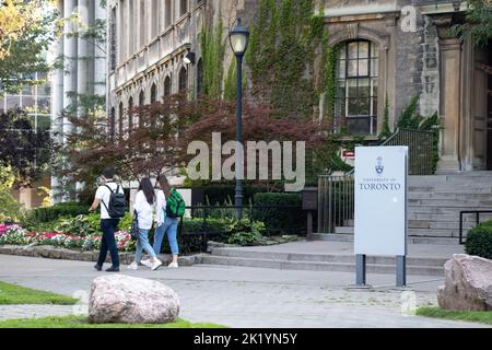 Students walk by a building with a sign for the University of Toronto, seen while on the campus on a sunny afternoon. Stock Photo