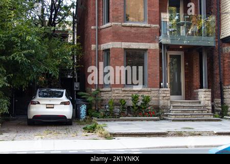 A Tesla Model Y, Tesla's best-selling car model, is seen parked at an older brick home while charging. Stock Photo