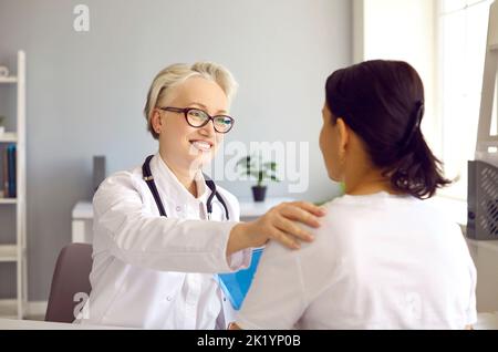 Positive senior female doctor in medical office congratulating her patient on recovery. Stock Photo