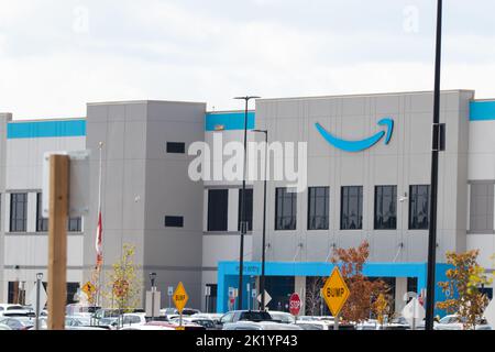 The entrance to an Amazon Fulfilment facility during the day; the famous Amazon logo in blue is on the front of the building. Stock Photo