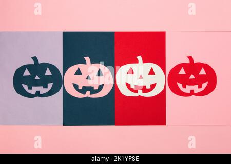 colorful carved pumpkins lined up on colorful background, creative halloween concept, flat lay, paper craft Stock Photo
