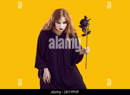 Portrait of crazy and creepy Halloween woman sneaking up with black rose in her hand. Stock Photo