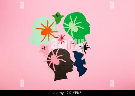 colorful paper head with colorful spiders, ghosts and bat, halloween colorful design, flat lay, paper craft, pink background Stock Photo