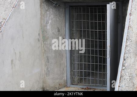 Open door to the cellar with bars in an old stone building. Stock Photo