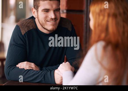 Hes totally smitten. a young affectionate couple holding hands while on a date. Stock Photo