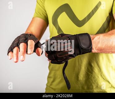 Wearing, putting on sport workout gloves close up for palm and wrist protection in gym. photo Stock Photo