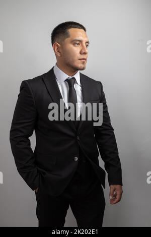 elegant latin young man with short hair and beard, business clothes, suit, shirt and tie, fashion and lifestyle in studio Stock Photo