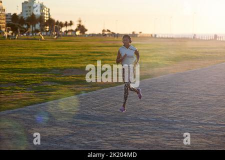 Enjoying her sunset running session. A young woman exercising outdoors at sunset. Stock Photo