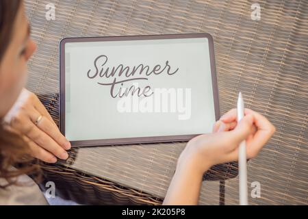 Calligrapher Young Woman writes phrase on digital tablet. Inscribing ornamental decorated letters. Calligraphy, graphic design, lettering, handwriting Stock Photo