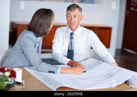 Discussing the finer details of the plans. two mature architects discussing blueprints in an office. Stock Photo