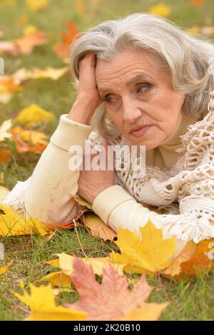Senior sad woman in the park in autumn Stock Photo