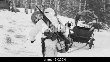 German Wehrmacht Infantry Soldier In World War II Soldiers Running With Anti-tank Gun Panzerschreck In Winter Forest. Historical Re-enactment. WWII Stock Photo