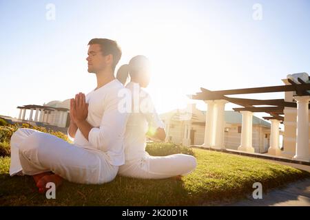 Blissful meditation in the sun. Full length shot of a young couple doing yoga outdoors. Stock Photo