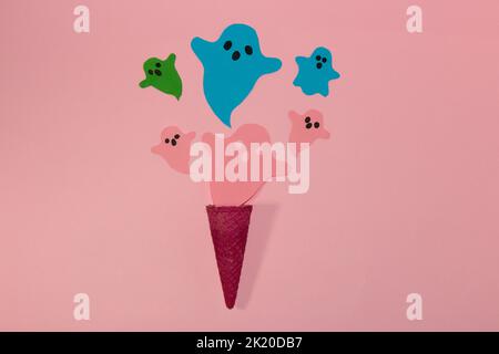 pink cornet from which colorful ghosts fly on a pink background, creative art halloween concept, flat lay, paper craft ghost Stock Photo